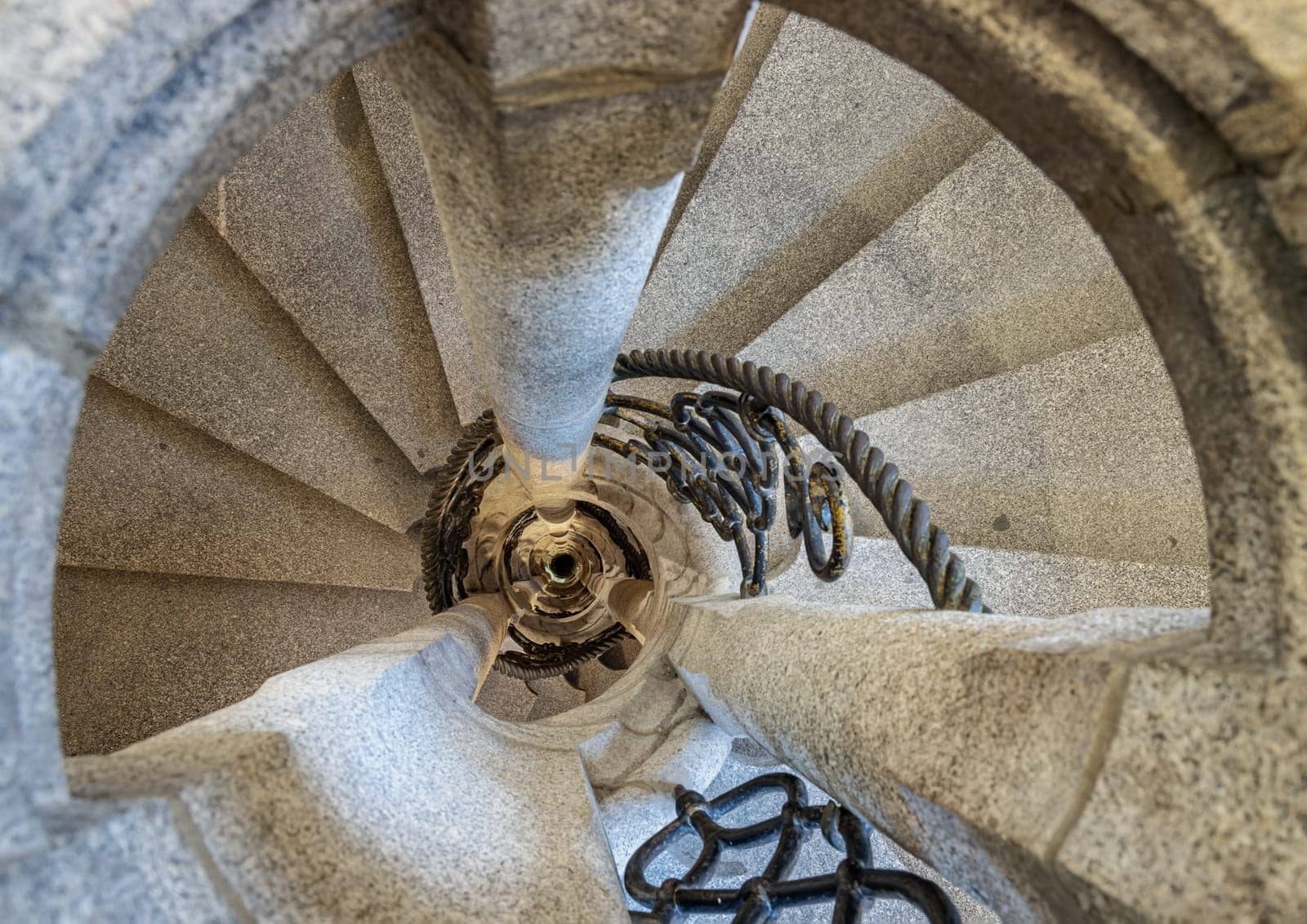 Munich, Germany - Dec 21, 2023 - Upside view of The old stone spiral staircase with iron railing inside columnar structures. Ladder decoration interior of building, Copy space, Selective focus.