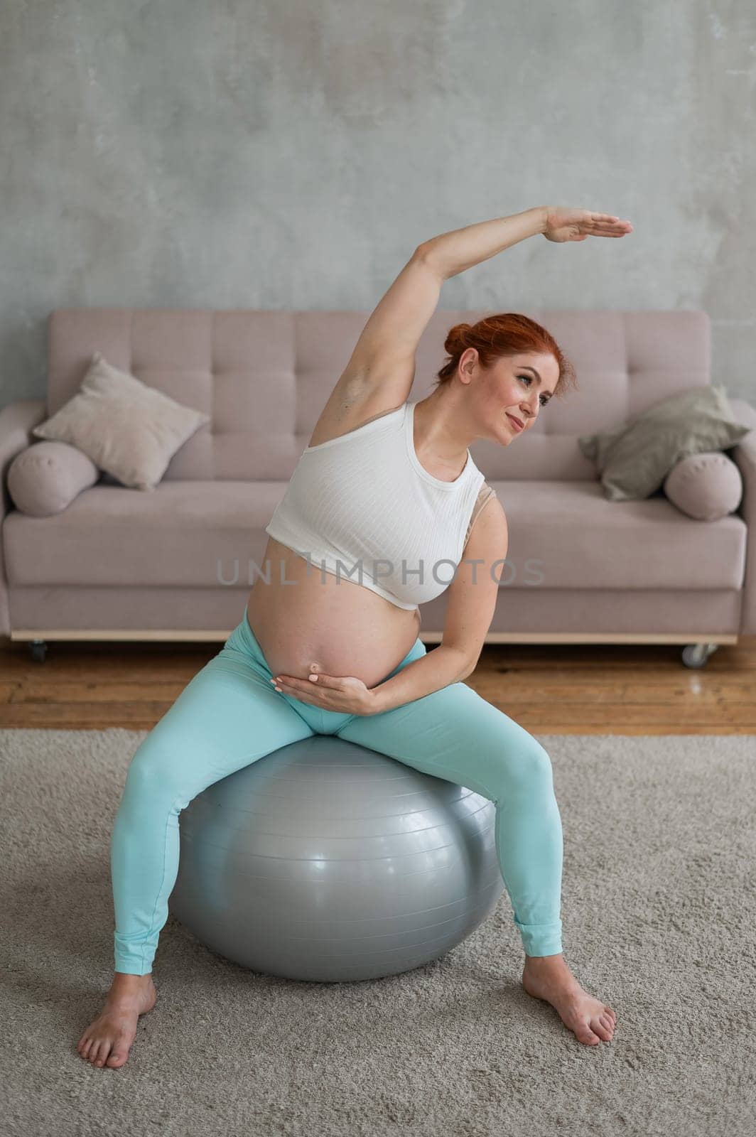 Pregnant woman doing lateral bends on a fitball at home