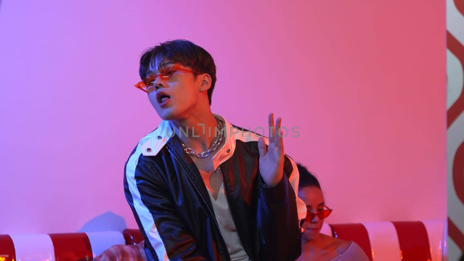 Attractive asian street dancer perform freestyle movement with neon light. Professional performer practicing moving to hip hop music with diverse friends or team at studio with led light. Regalement.