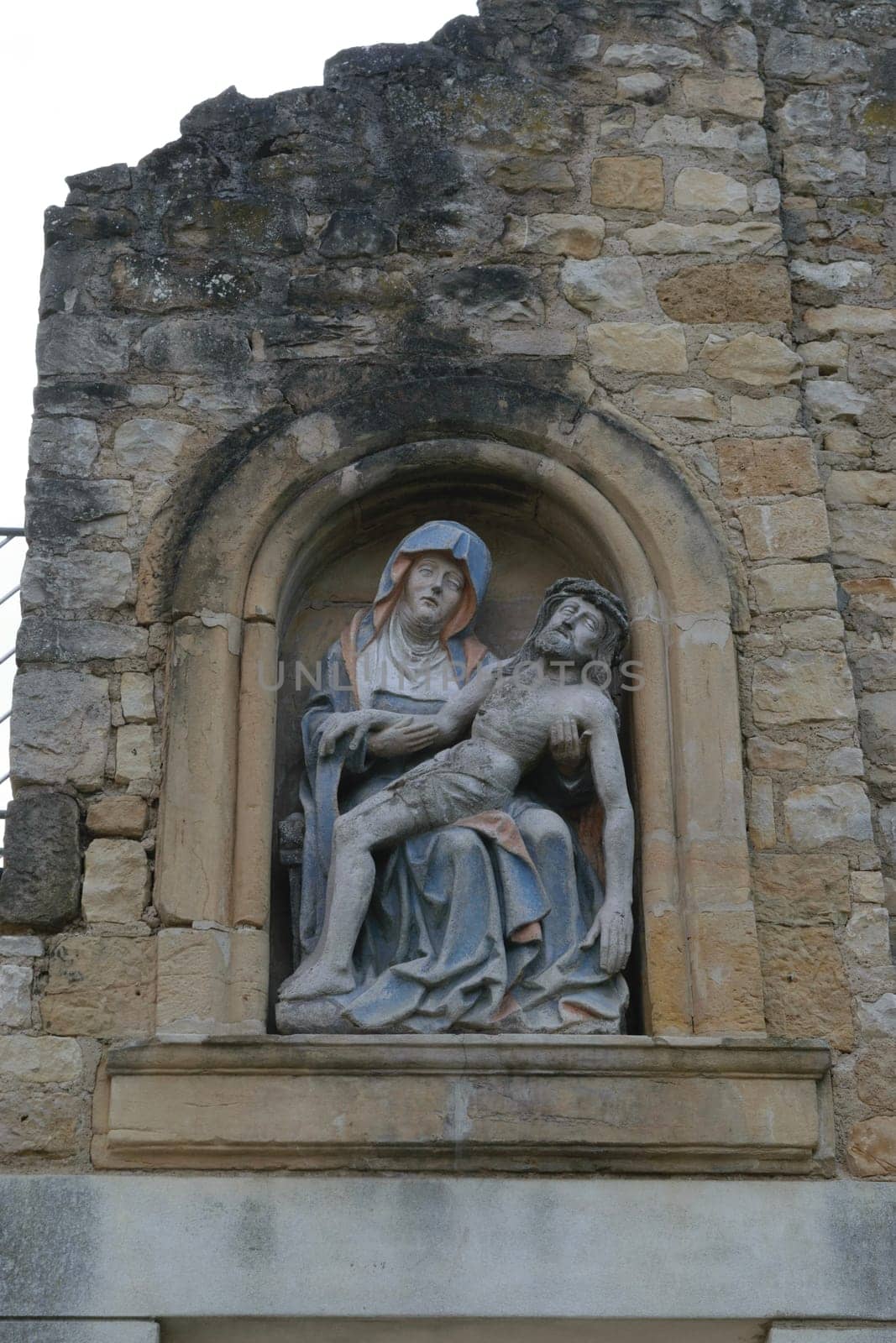 A relief of Jesus and Mary on a deteriorating stone wall.