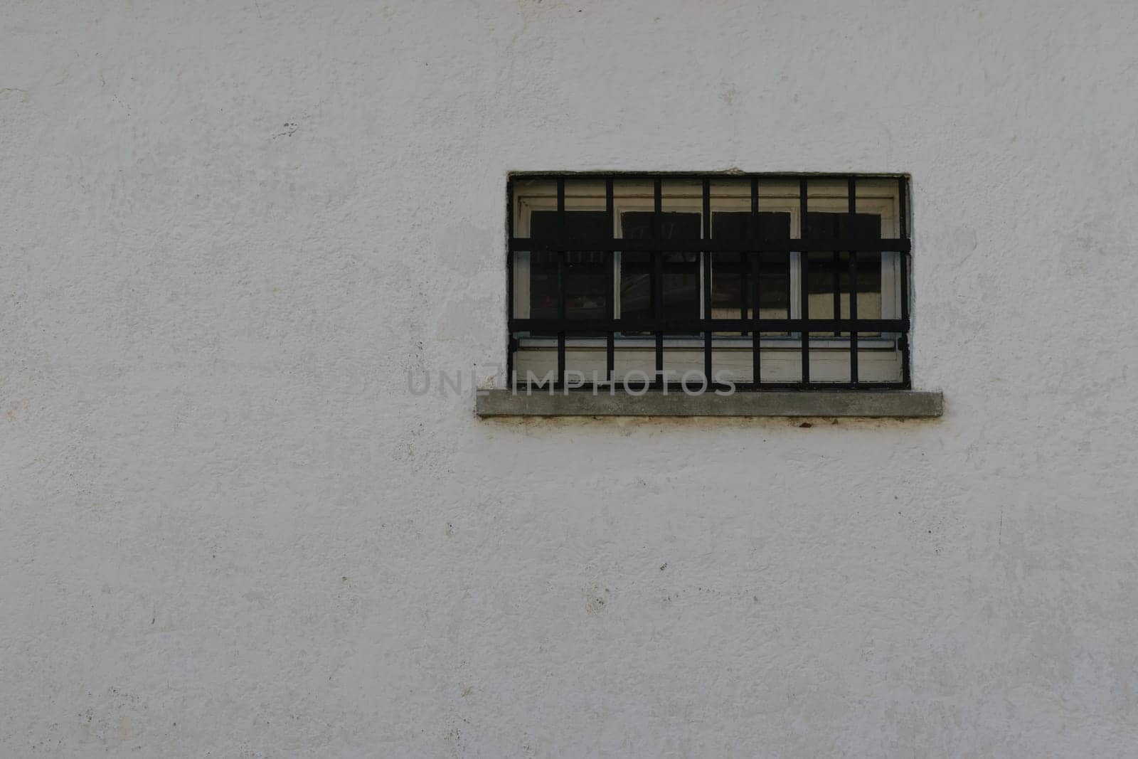 A small barred window on a plain white wall.