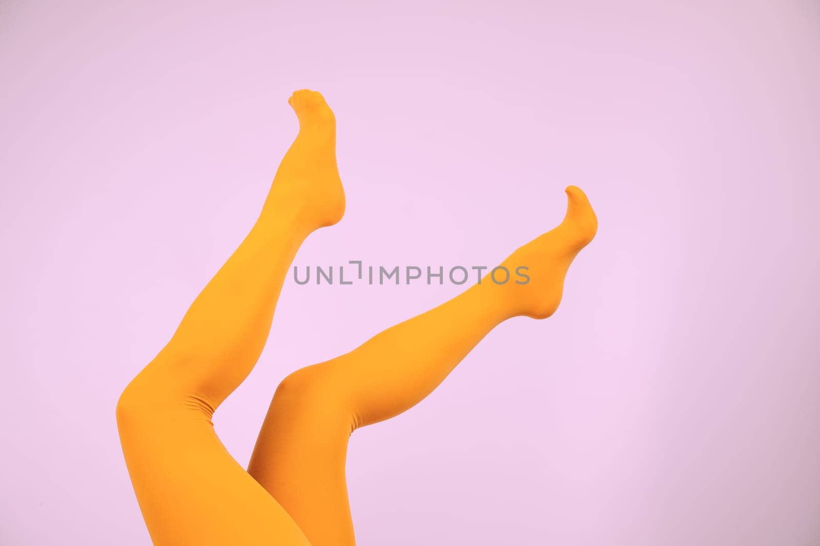 Female legs in ocher tights on a pink background