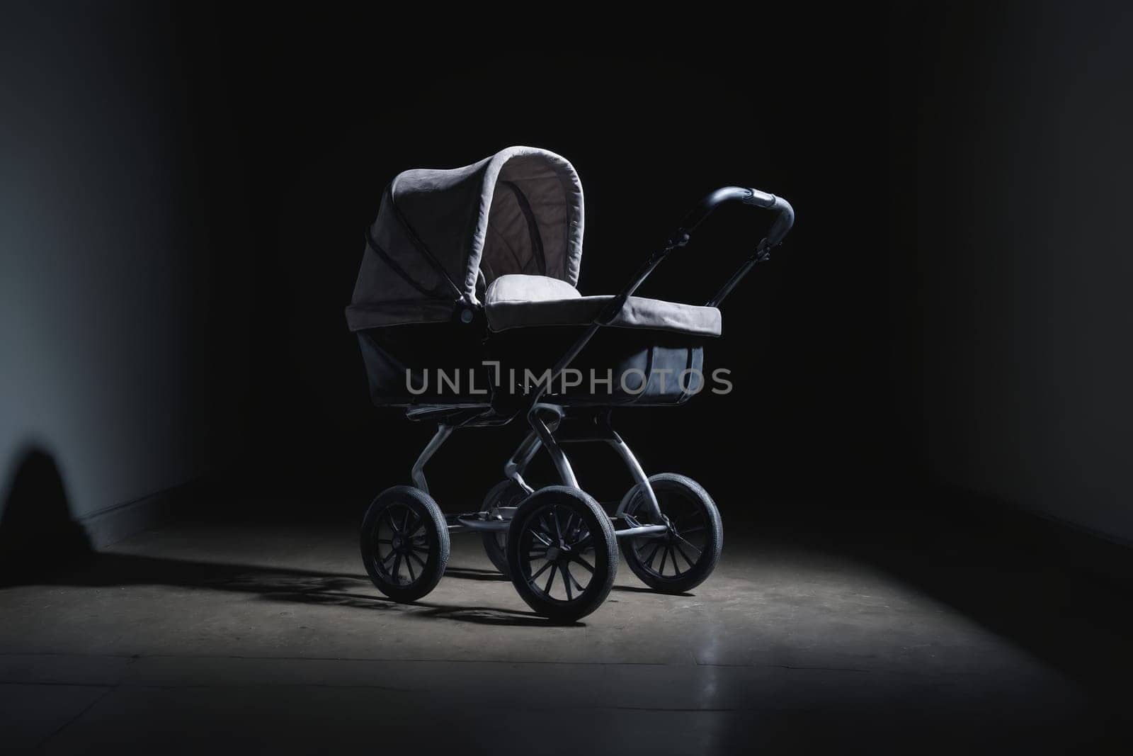 Bathed in a spotlight's cold gleam against an otherwise empty wall, stands an antique baby stroller. This black and white image captures the eerie loneliness and nostalgic overtones imprinted in its silhouette and the surrounding quiet.