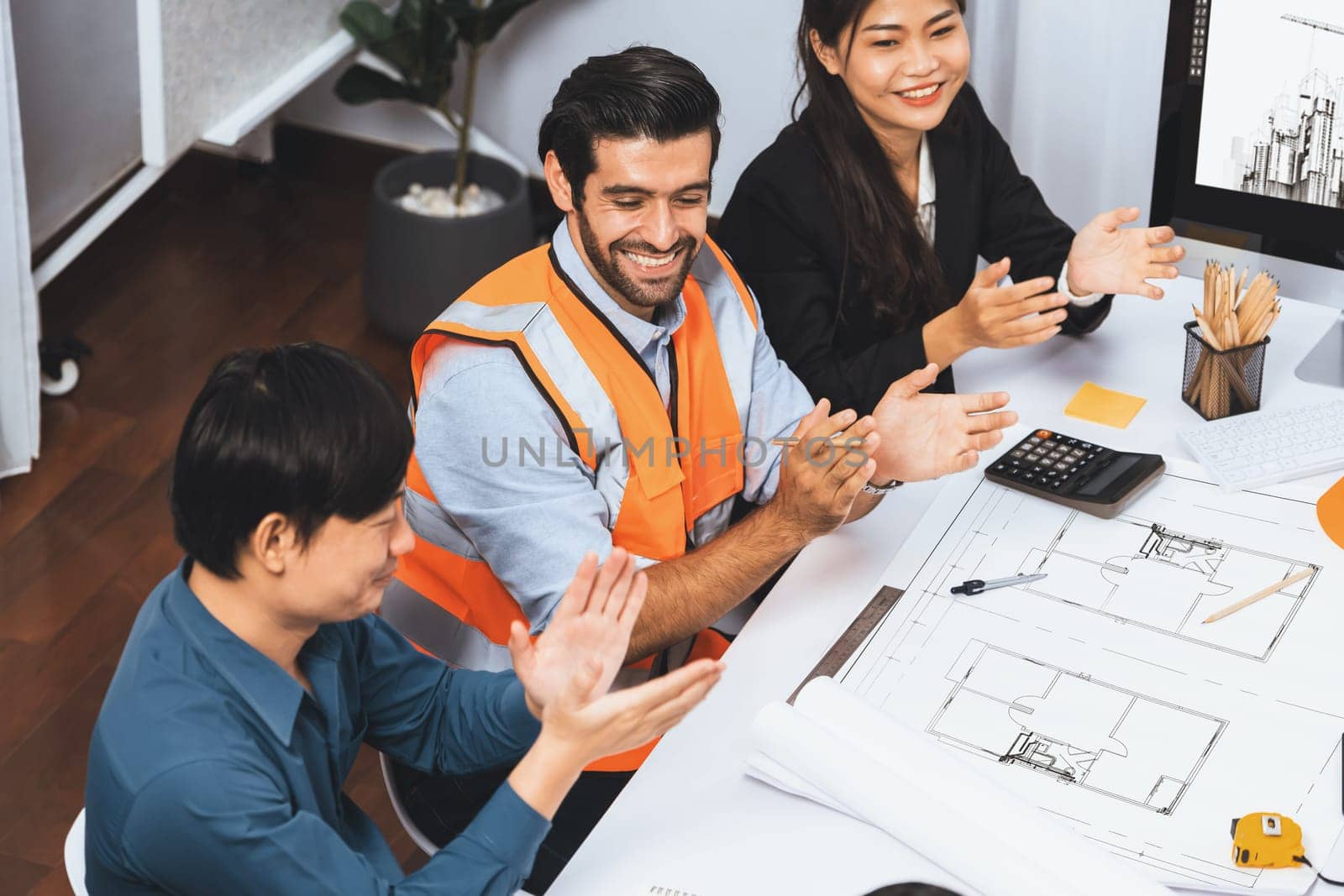 Diverse group of civil engineer and client feels excited and applauding after successful agreement on architectural project, review construction plan and building blueprint at meeting table.Prudent