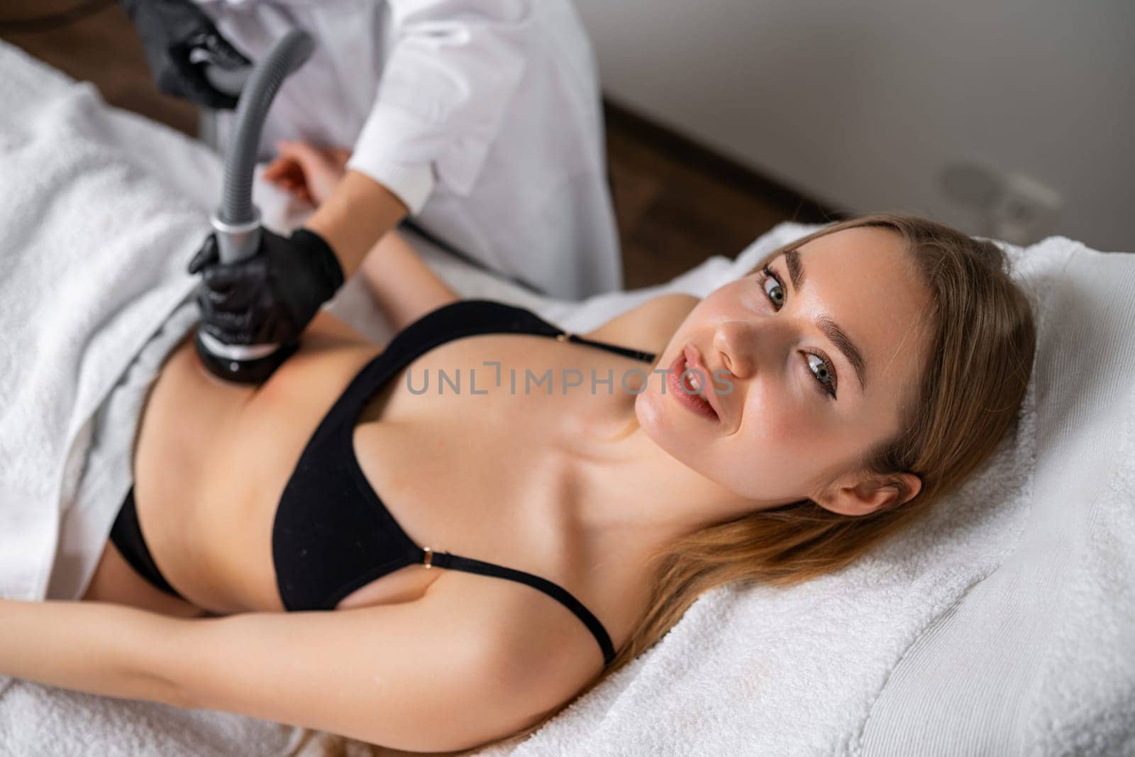 Close cosmetologist using ultrasound device while performing lifting procedure on woman belly by vladimka