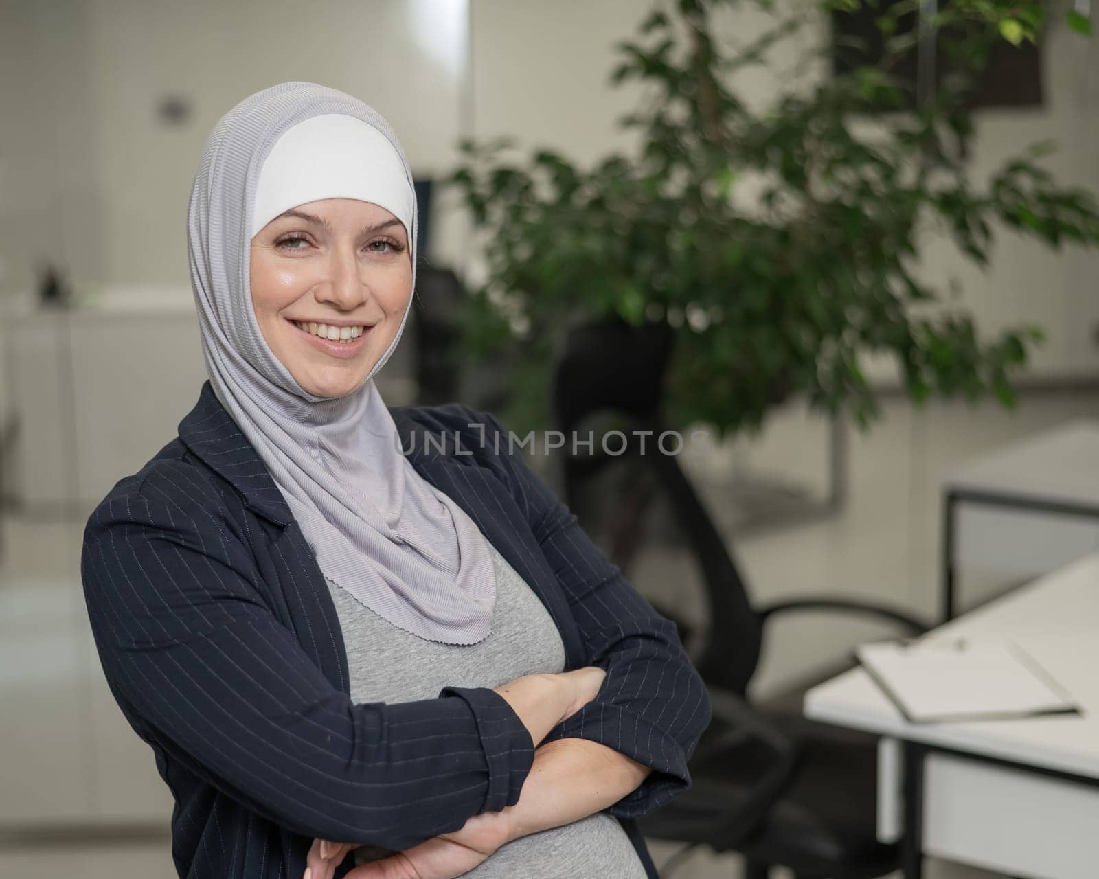 Pregnant Caucasian woman in hijab working in the office