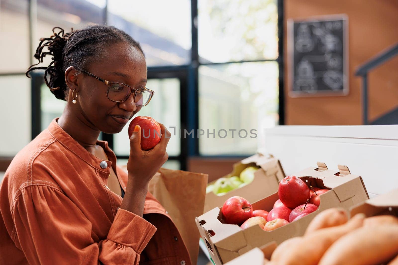 Customer smells fresh red apple in store by DCStudio