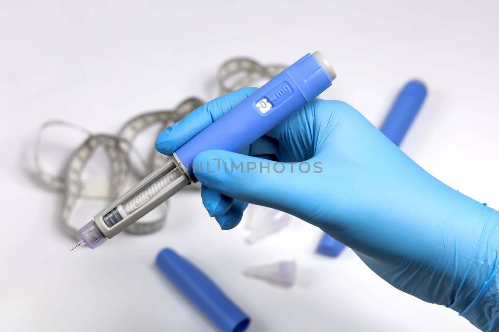 Hands in blue surgical gloves holding Ozempic Insulin injection pen for diabetics.