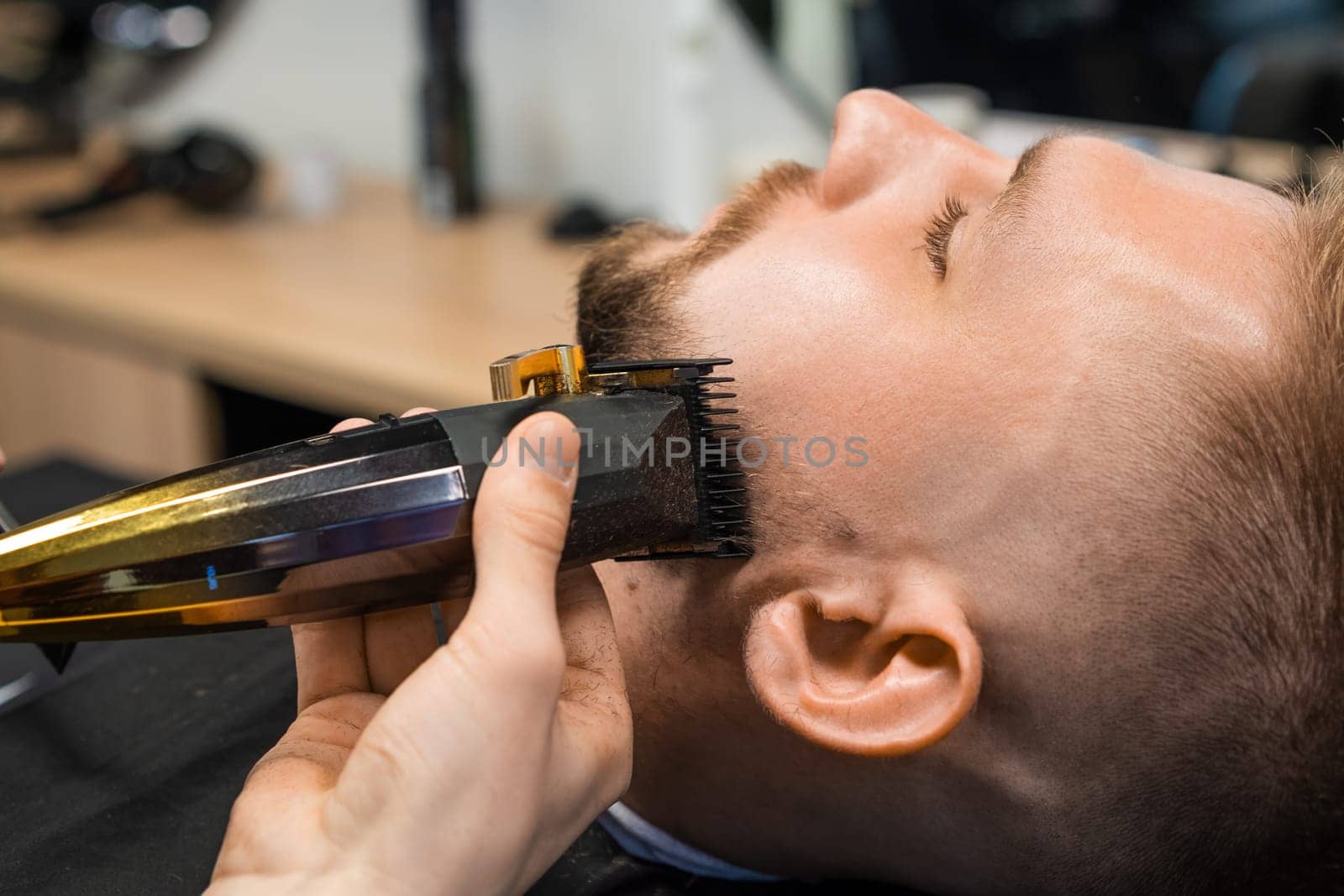 Barbers skilled hand deftly trims a clients beard using a precision trimmer in the barbershop