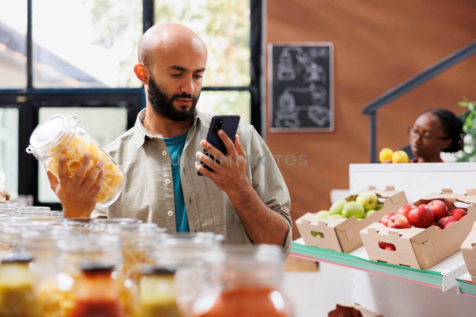 Bearded man in closeup using smartphone to search for recipes and prices at nearby eco friendly shop. Middle eastern shopper browsing on internet for advice on sustainable healthy living.