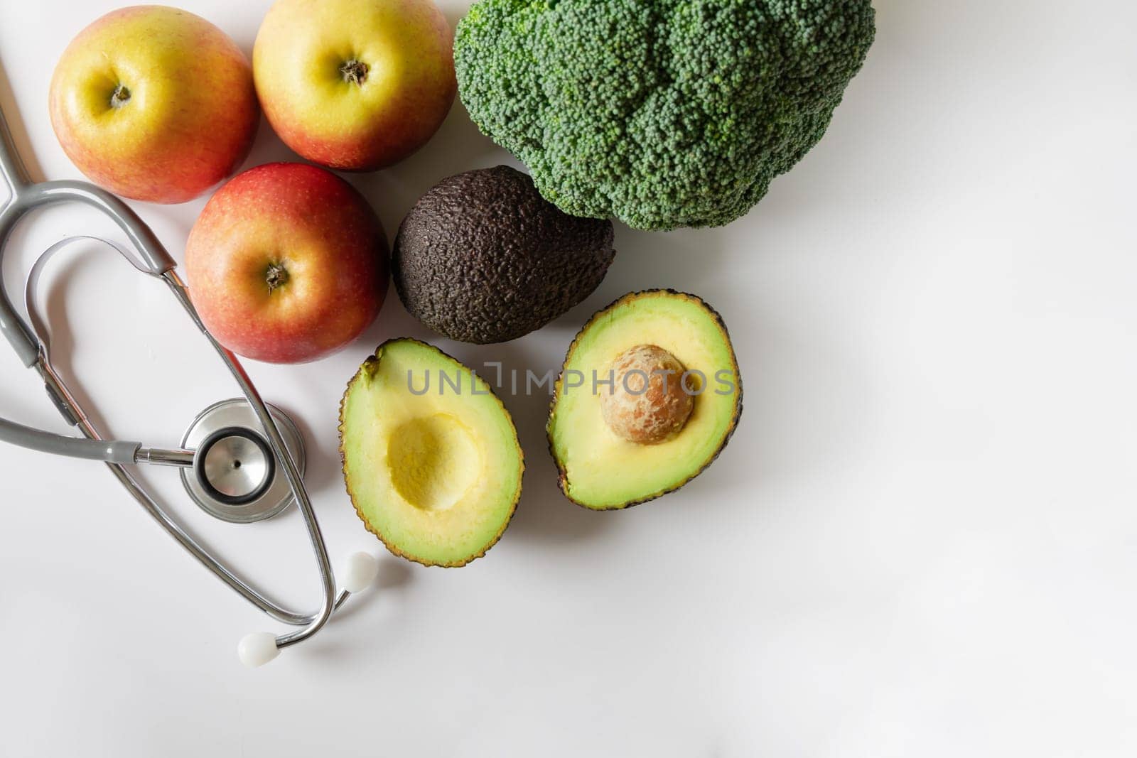 Healthy food concept. Fruit and vegetables and a statoscope laid out on a white background. High quality photo