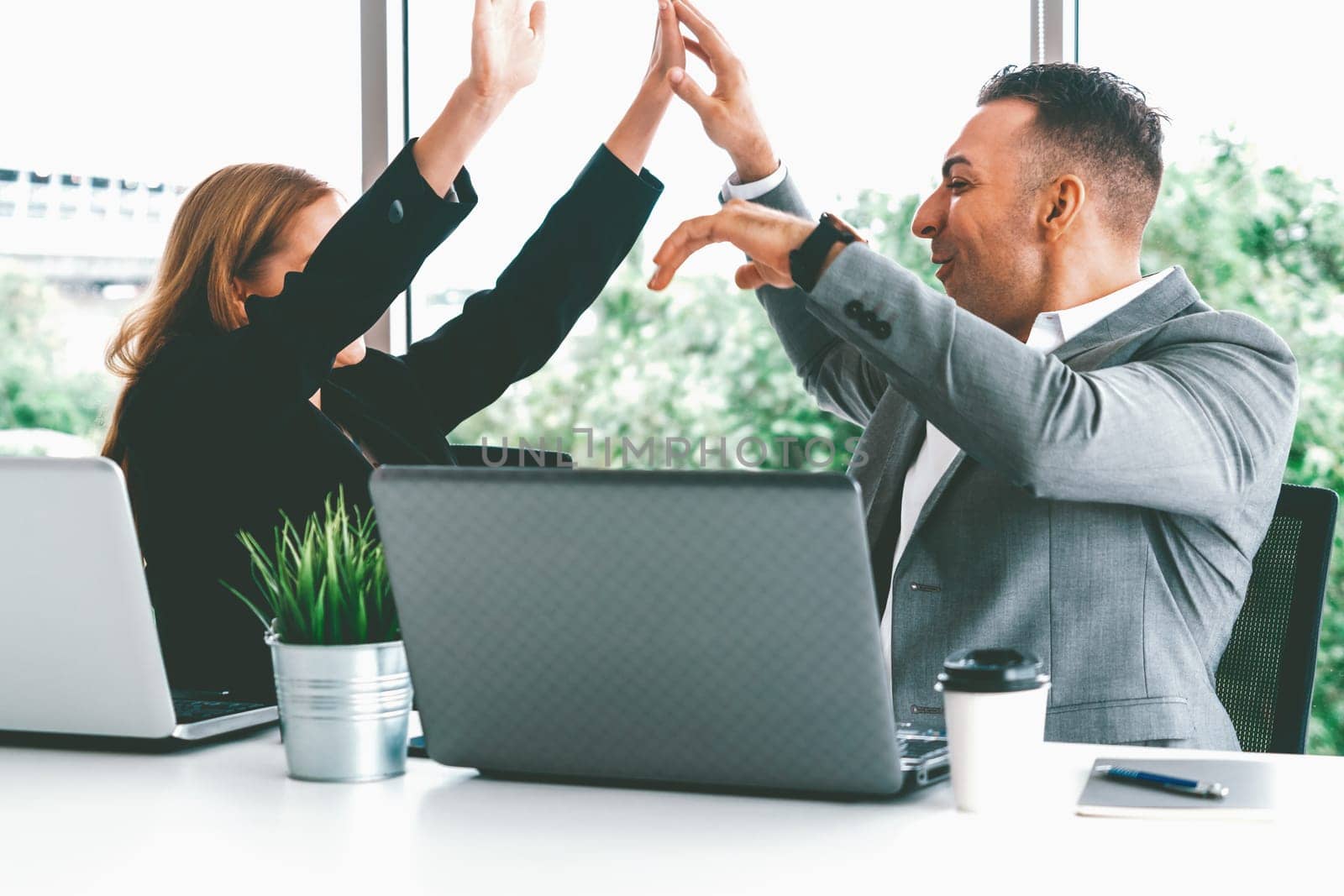 Success business partner - Businesswoman and businessman celebrating together in modern workplace office. People corporate teamwork concept. uds