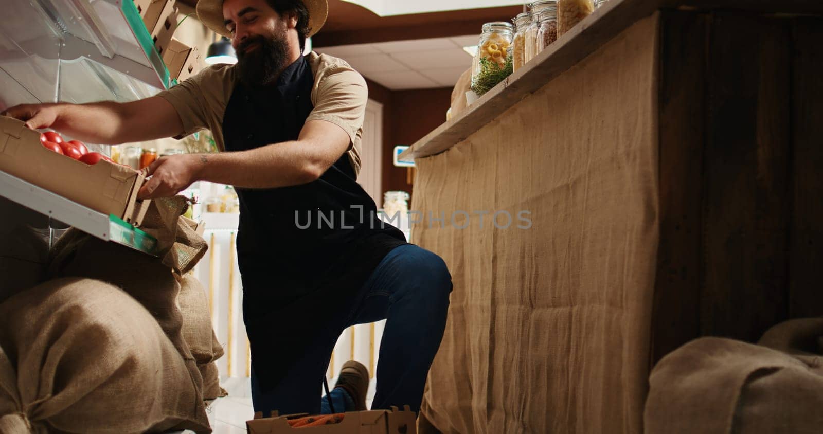 Storekeeper arriving in bio supermarket with freshly harvested natural food. Vendor restocks local neighborhood grocery shop with chemicals free vegetables while chatting with client, hip level shot