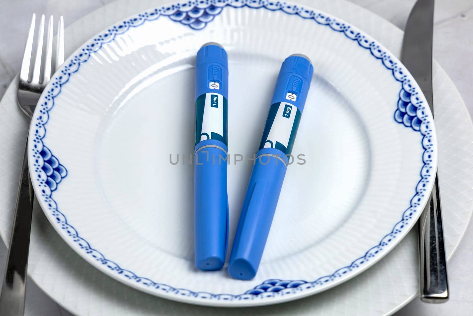 Ozempic Insulin injection pen or insulin cartridge pen for diabetics on a white plate. Medical equipment for diabetes parients.