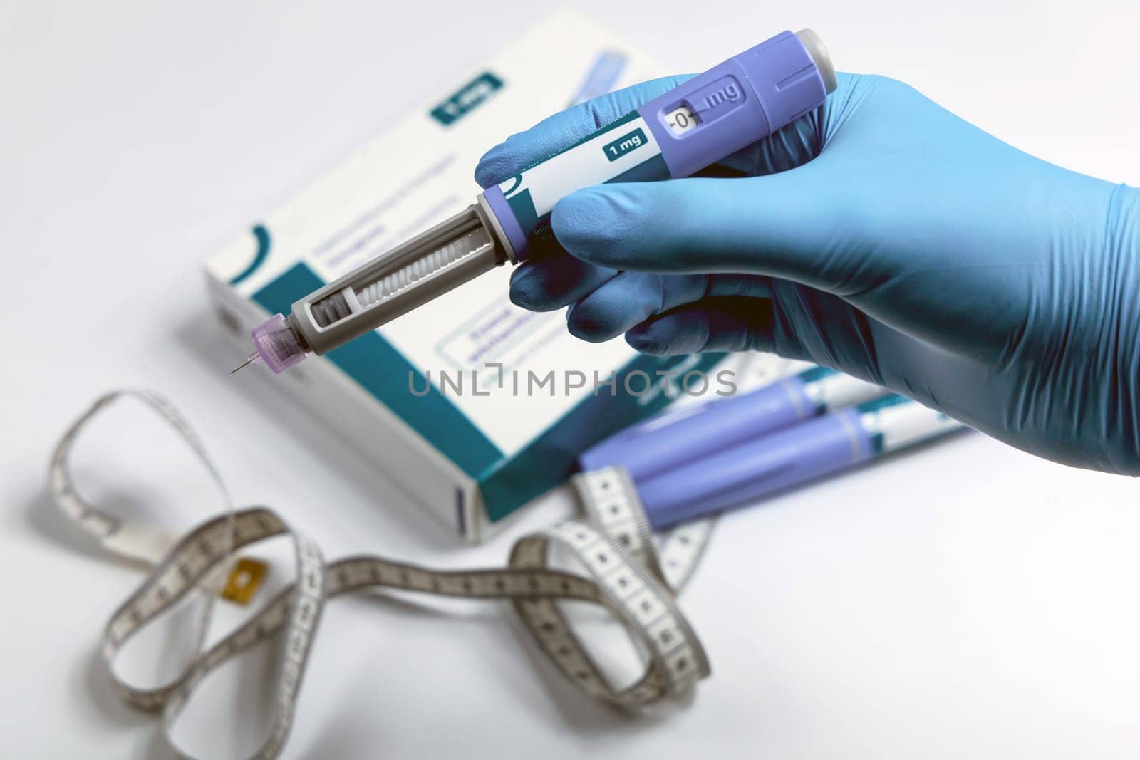 Hands in blue surgical gloves holding Ozempic Insulin injection pen for diabetics.