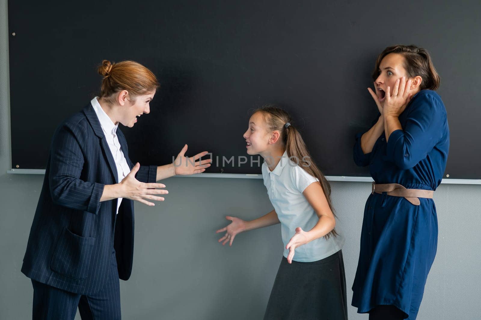 A female teacher and a student's mother yell at each other at the blackboard. The schoolgirl is crying. by mrwed54