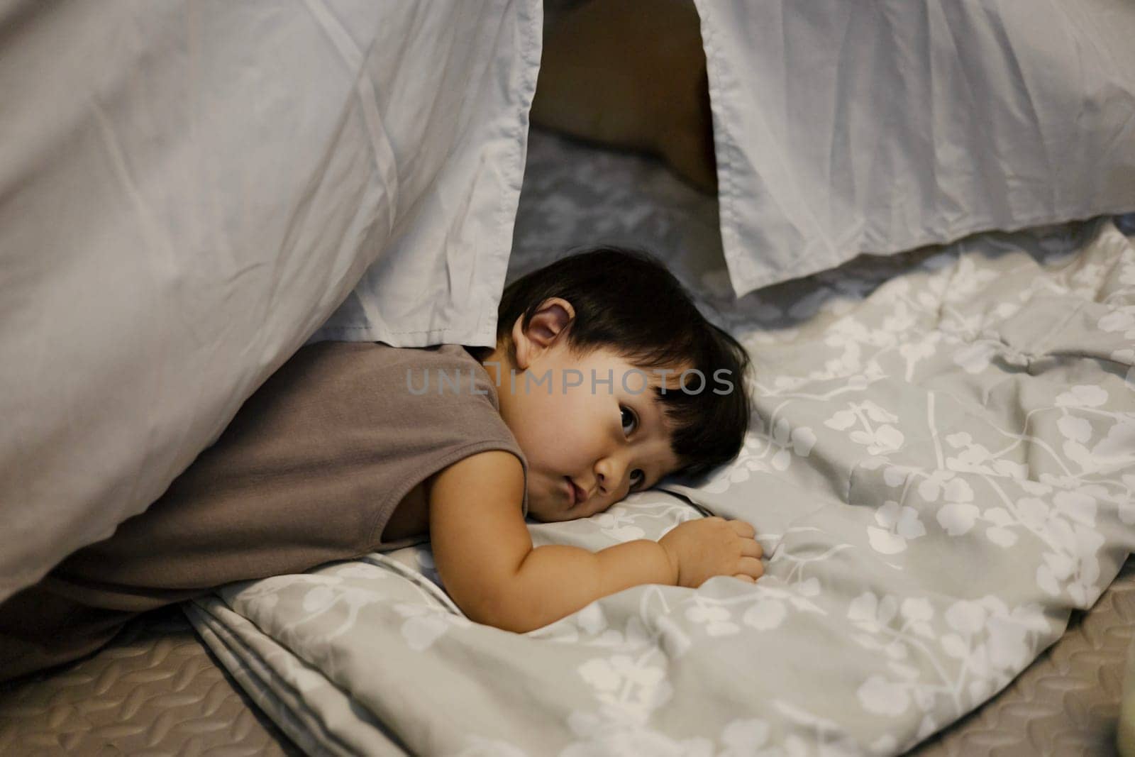 Little boy is lying in a wigwam. Little boy lying on the floor.