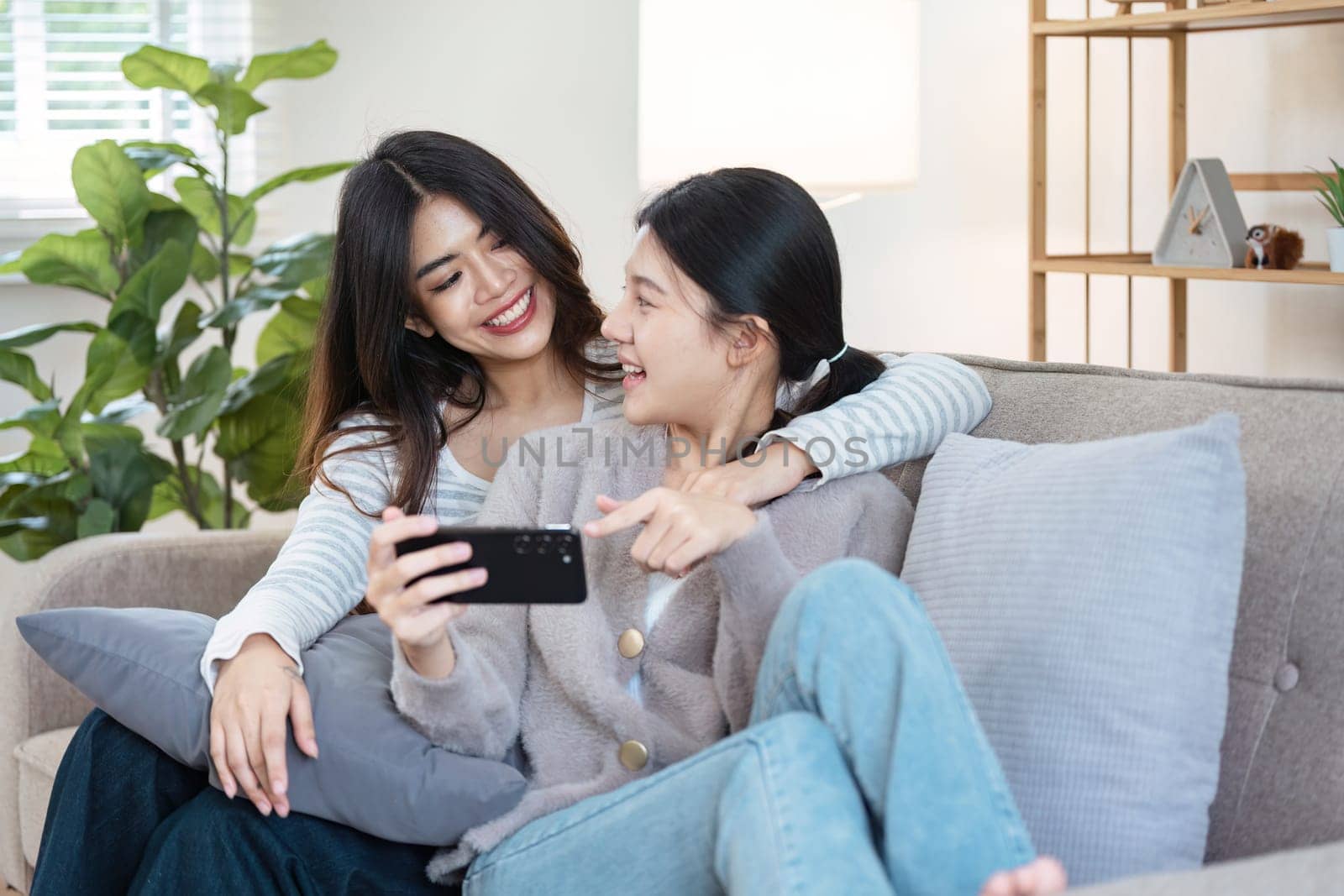 Happy woman lesbian gay lgbt couple enjoying fun gaming session on the couch at home.