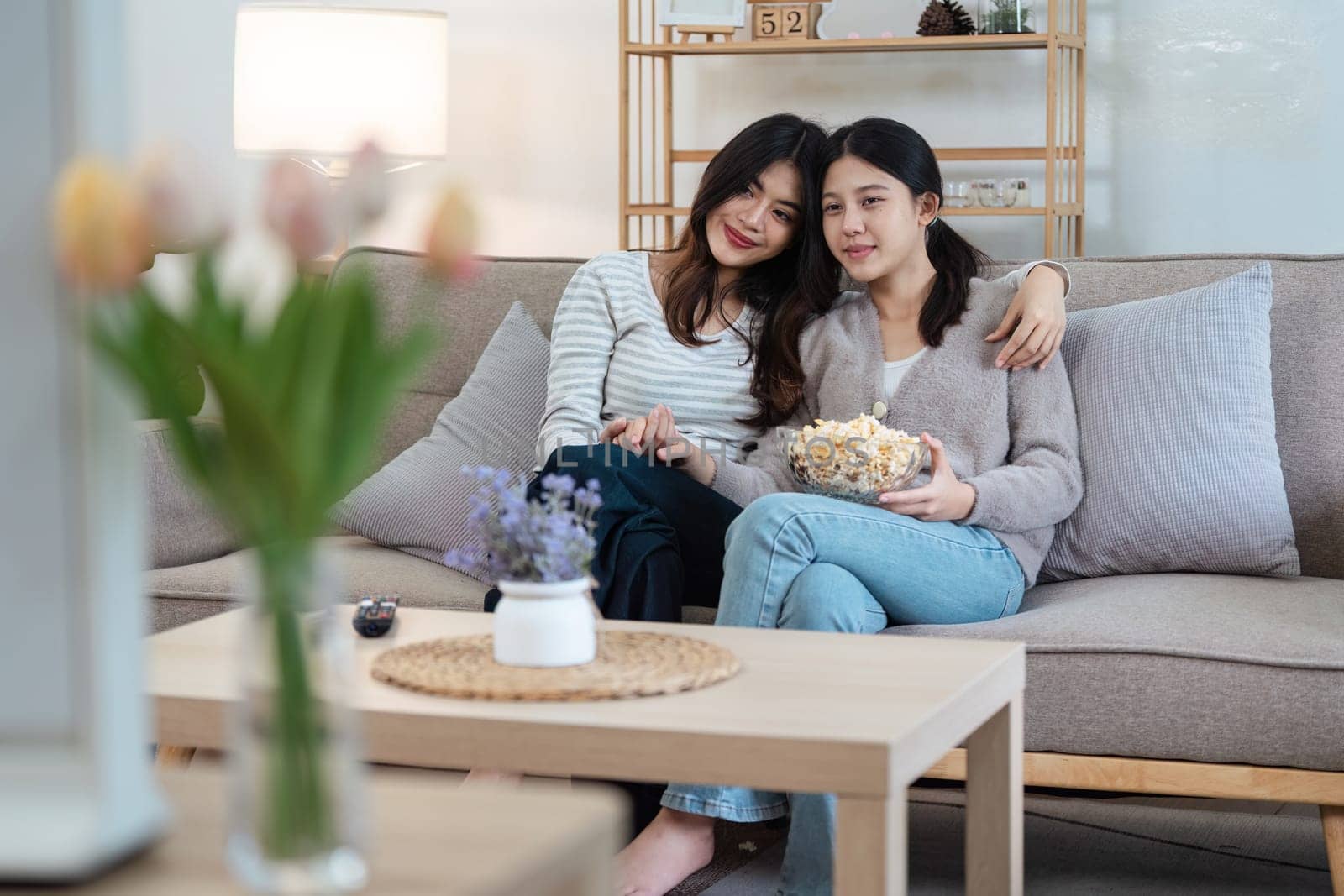 pride month Happy women lesbians lgbt couple spending time together at home in the evening, relaxing, watching movie together in the living room. LGBTQ couple concept.