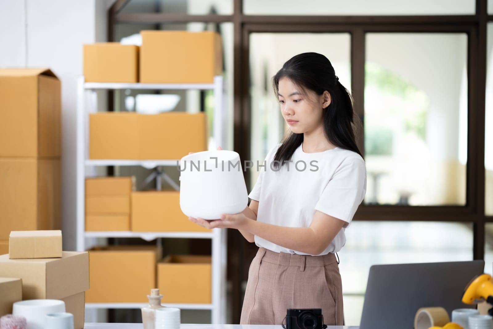 Attentive business owner thoroughly examining a product to ensure top quality before dispatch in her online shop workspace.