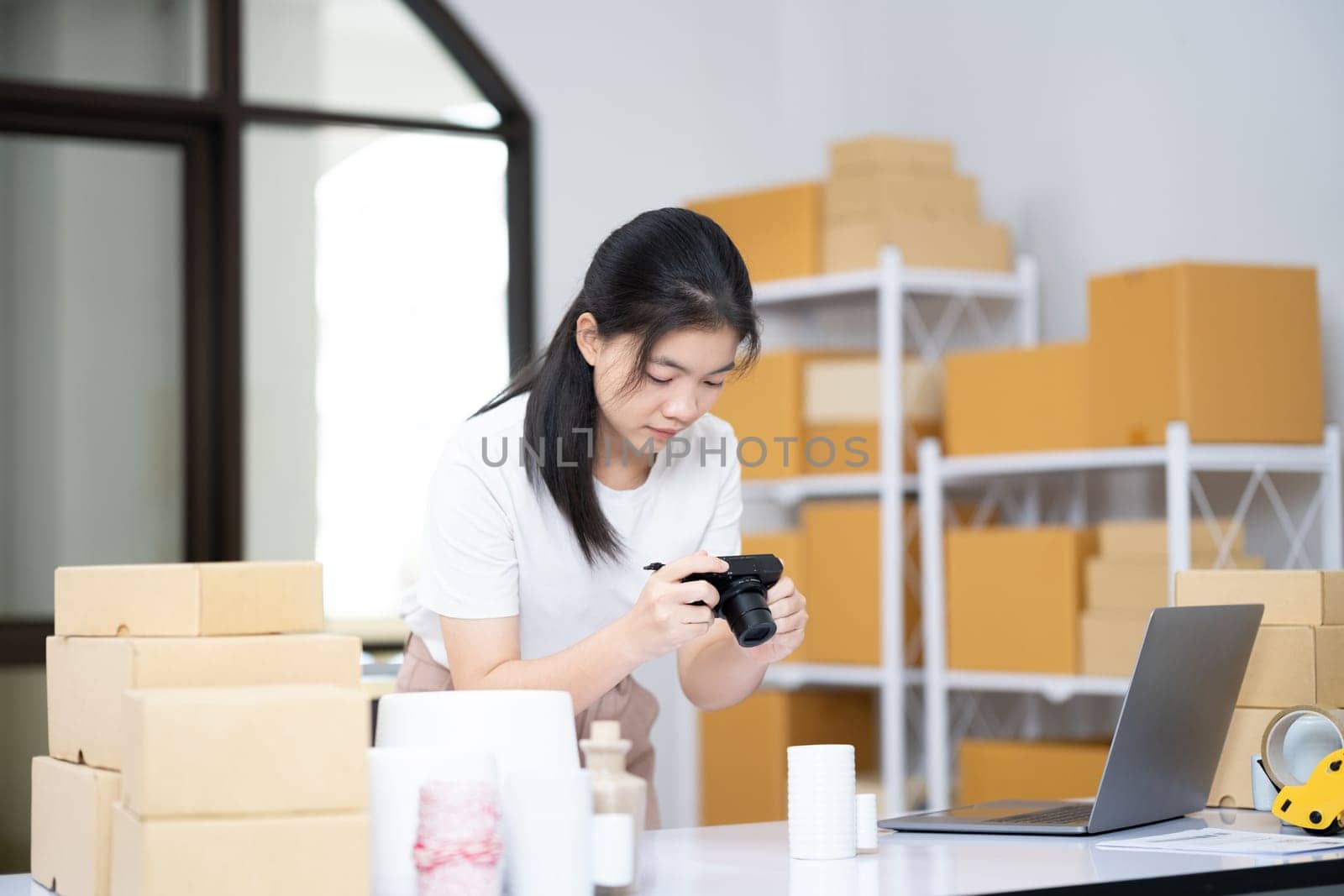 Young women taking photo of product with digital camera for post to sell online on the Internet and preparing pack product box. Selling online ideas concept