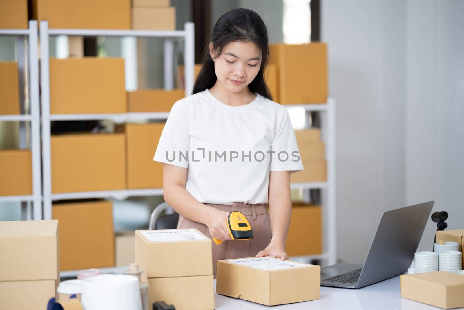 Hands scanning barcode on delivery parcel. Worker scan barcode of cardboard packages before delivery at storage. Woman working in factory warehouse scanning labels on the boxes with barcode scanner.