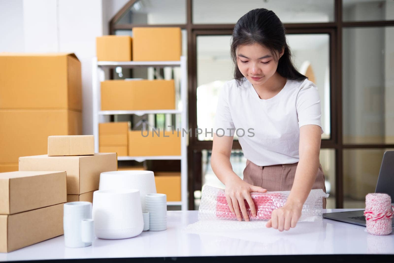 Young woman packing product for customer with cardboard box.