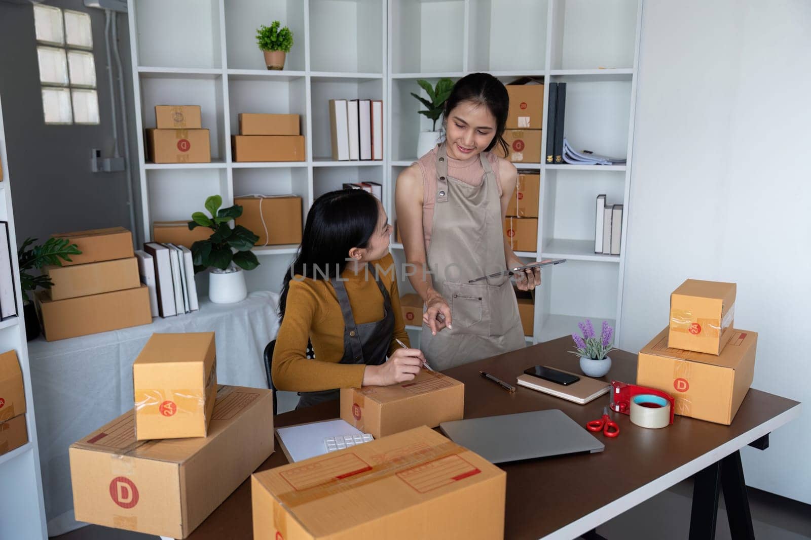 Asian women managing online store inventory and shipping orders. Concept of e-commerce business, teamwork, and logistics.