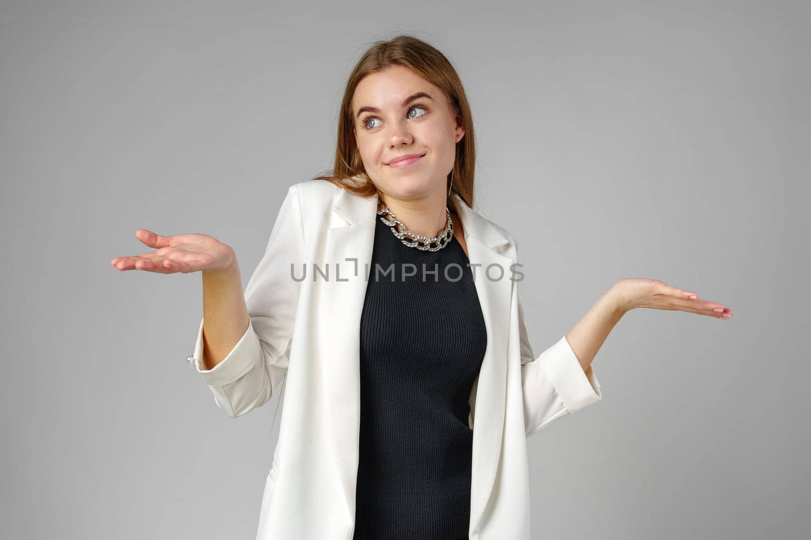 Young Woman Expressing Confusion With Hands Raised Against a Grey Background in studio