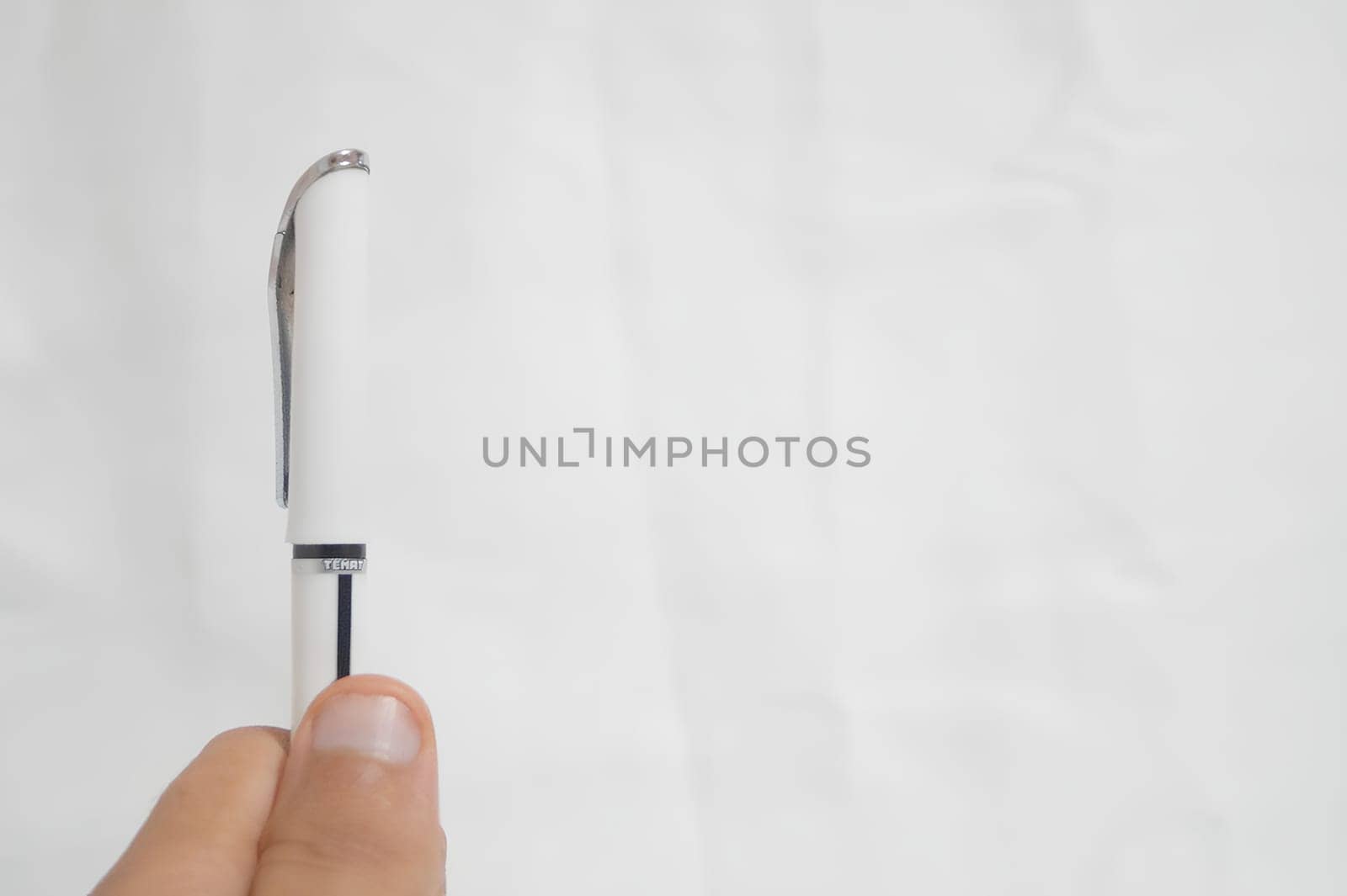 A pen is being held up in front of a white background. High quality photo