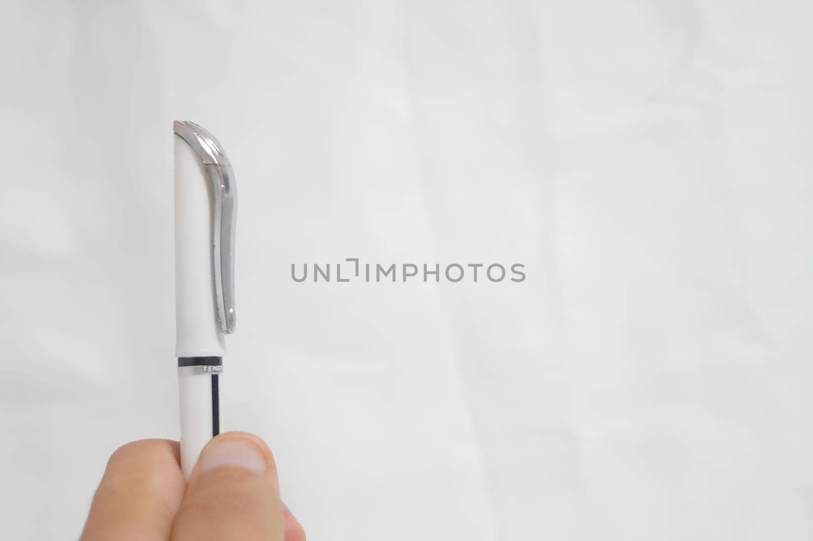 A pen is being held up with the cap off. High quality photo