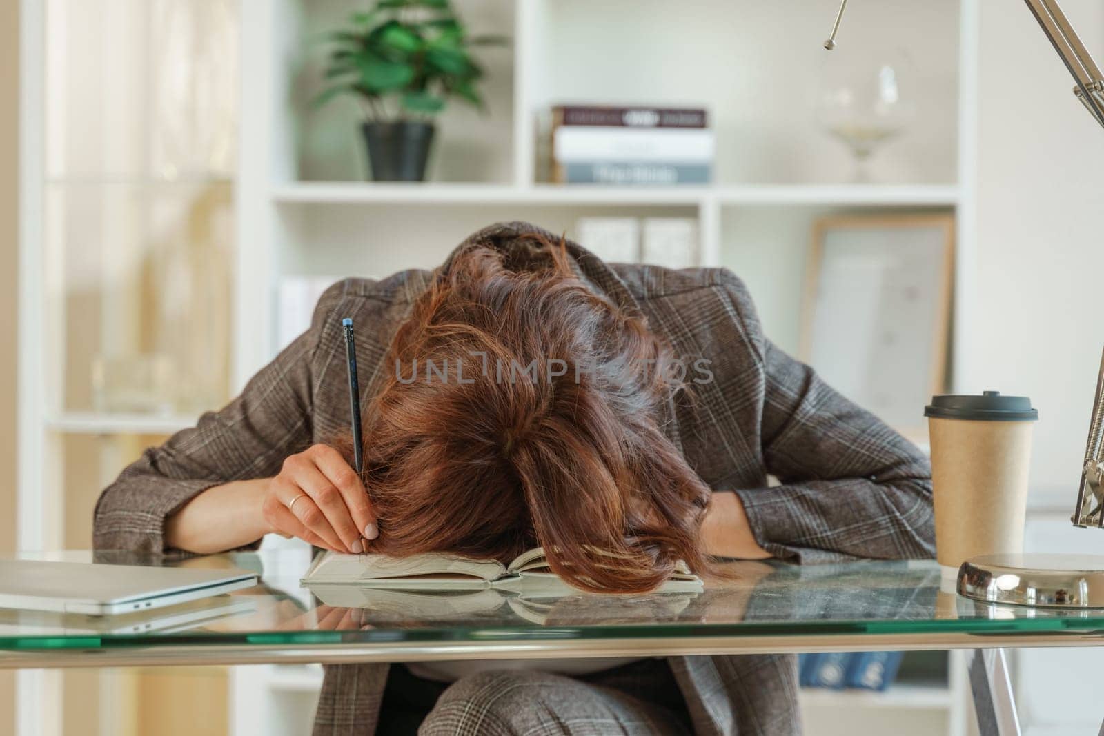 The woman is tired. Young tired woman put her head on the table, tired worker or student sitting exhausted on the table at home.