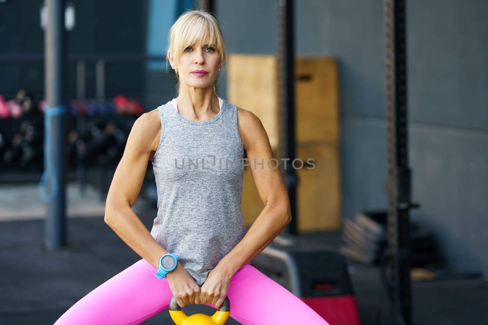 Pensive young female with kettlebell on gym by javiindy