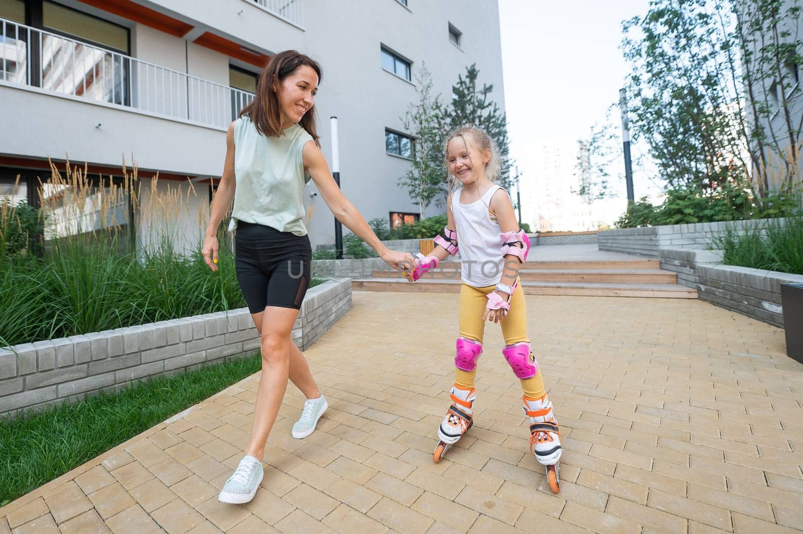 Mother helps daughter learn to roller skate. by mrwed54