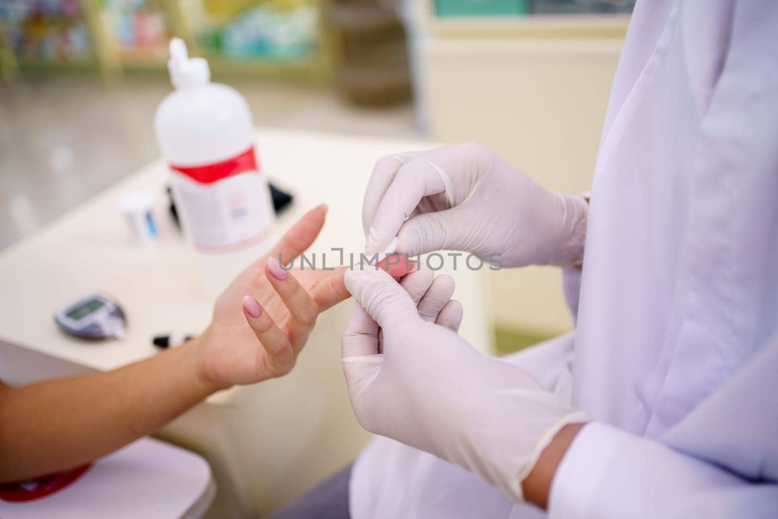 Closeup of standing anonymous pharmacist hands, in medical gloves testing blood of sitting faceless lady customer while diagnosing with tool diabetes and sugar.