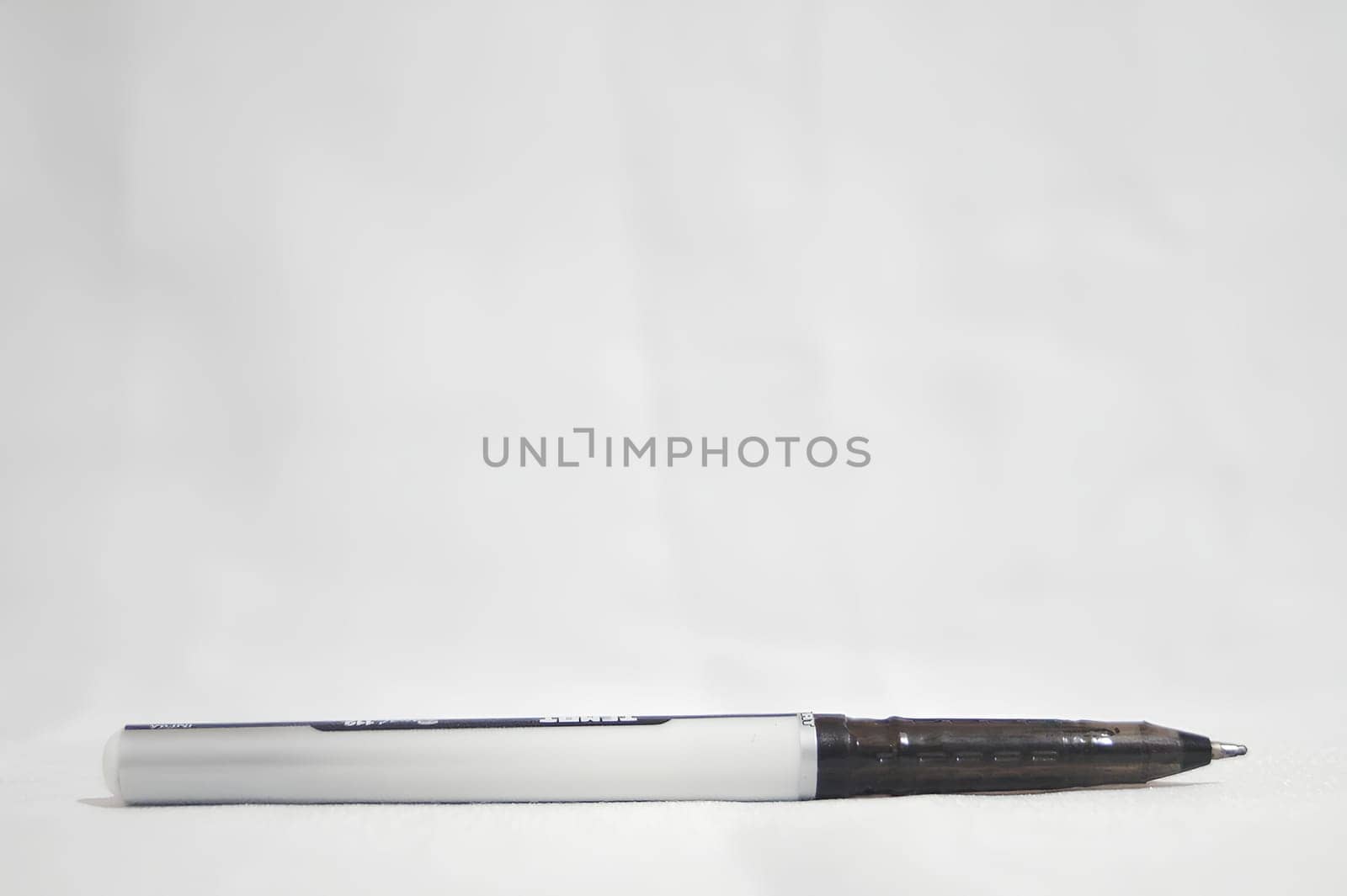 A black pen with a white tip sits on a white surface. High quality photo