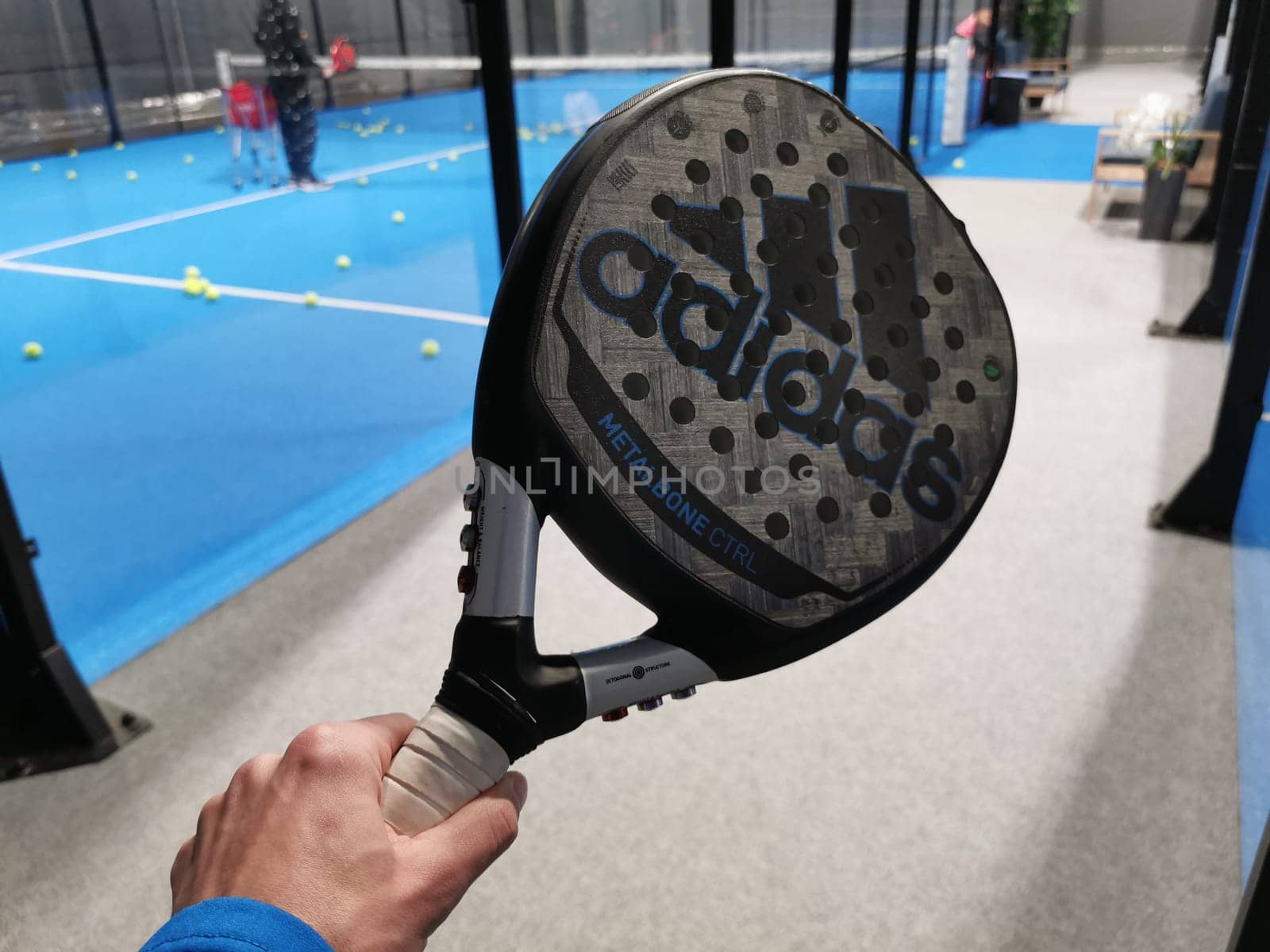 Ukraine Kyiv, April 11 2024: Padel racket adidas and padel ball on a green court . High quality photo