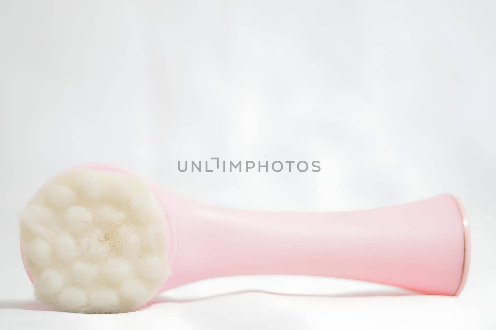 A pink brush with white bristles is laying on a white surface. High quality photo