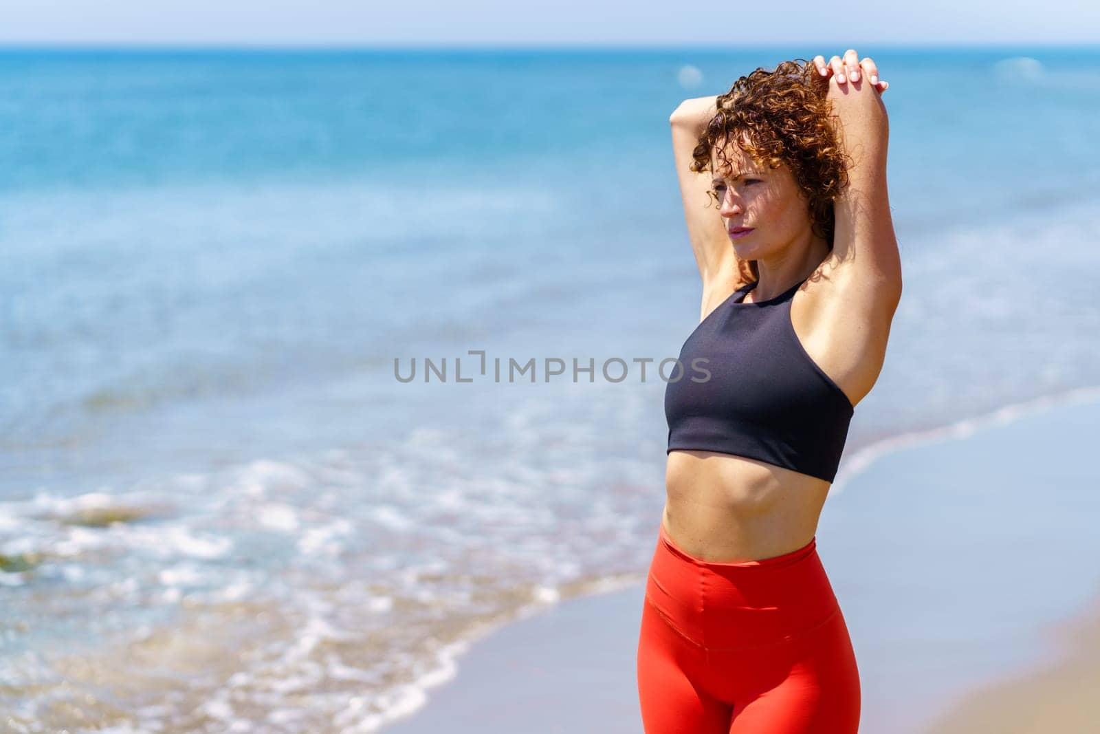 Pensive woman stretching on seashore by javiindy