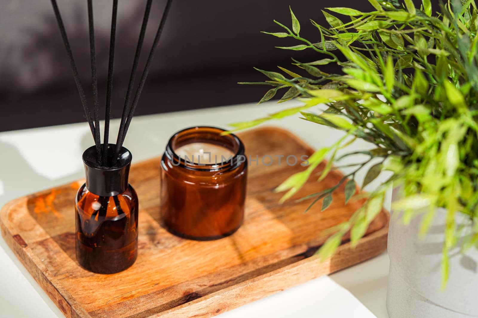 Aromatic reed freshener and candle on table in room close up