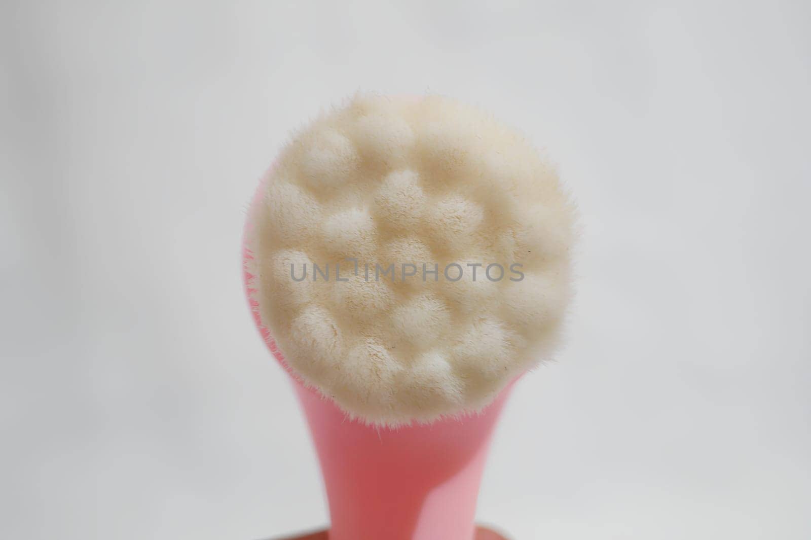 A pink brush with white bristles is shown in a close up. High quality photo