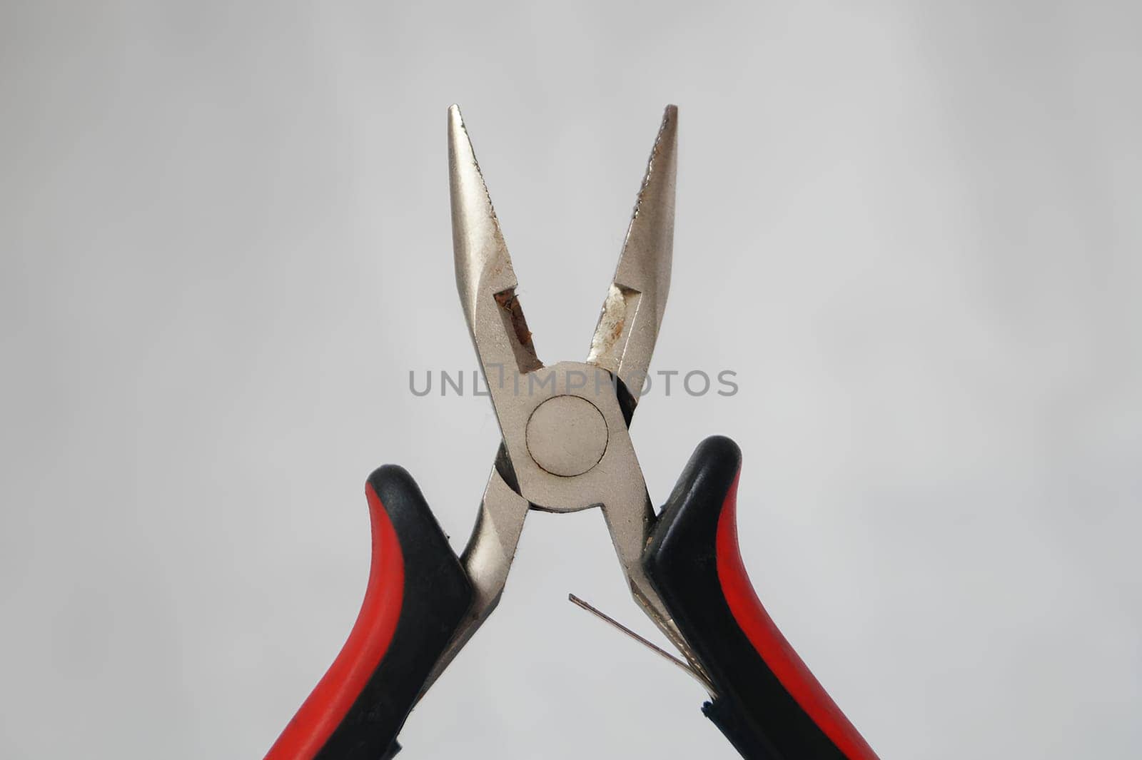 A pair of pliers with a red handle and a black handle. High quality photo