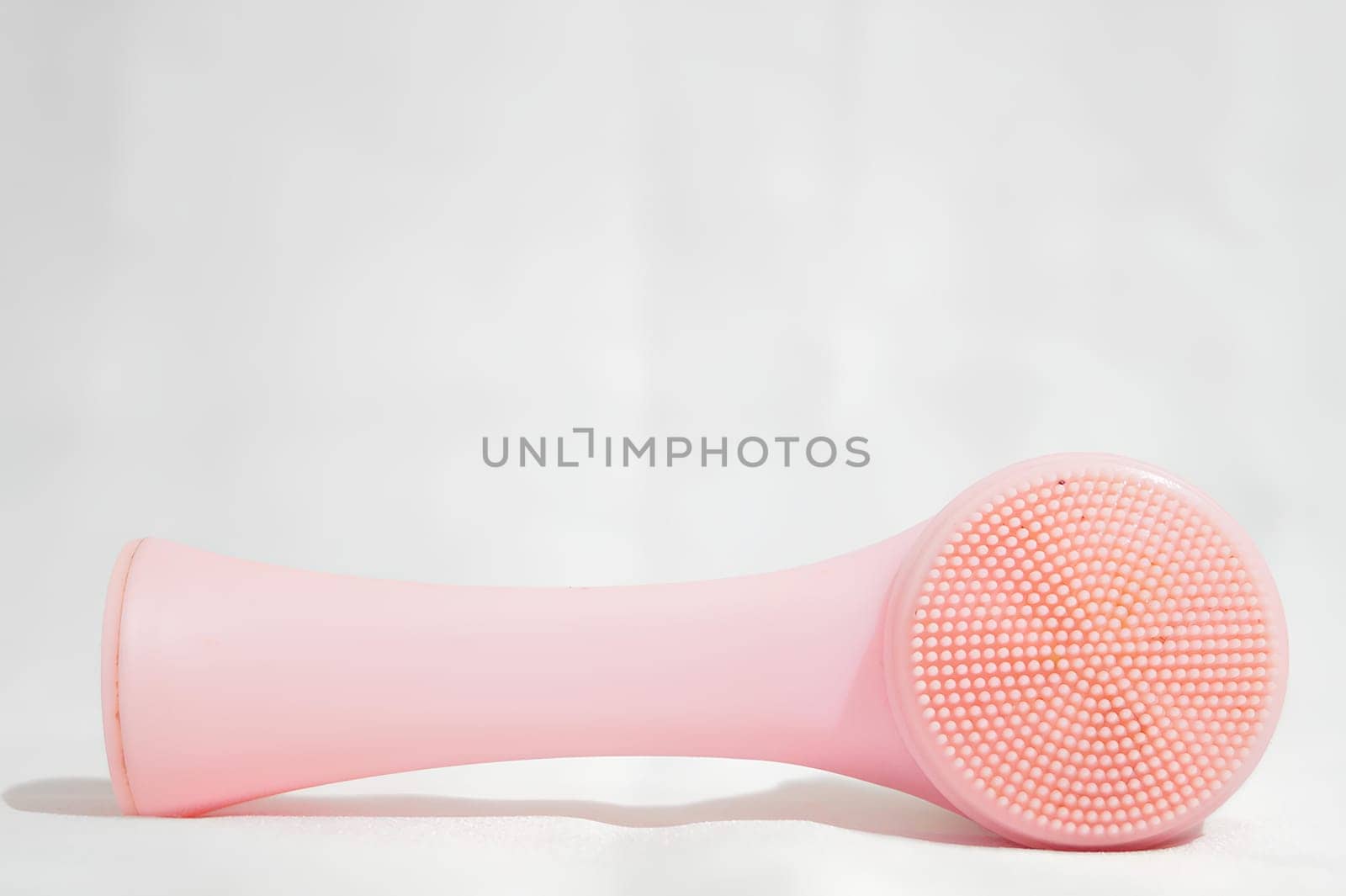 A pink brush with a white handle sits on a white surface. High quality photo