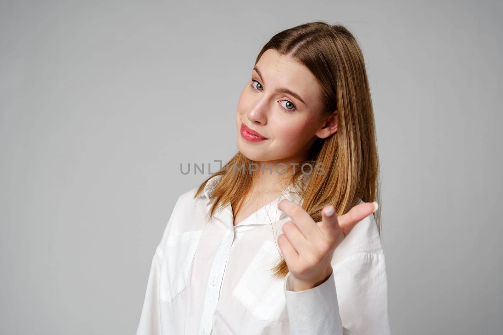 Young Woman in White Shirt Gesturing Come Here With Both Hands Indoors