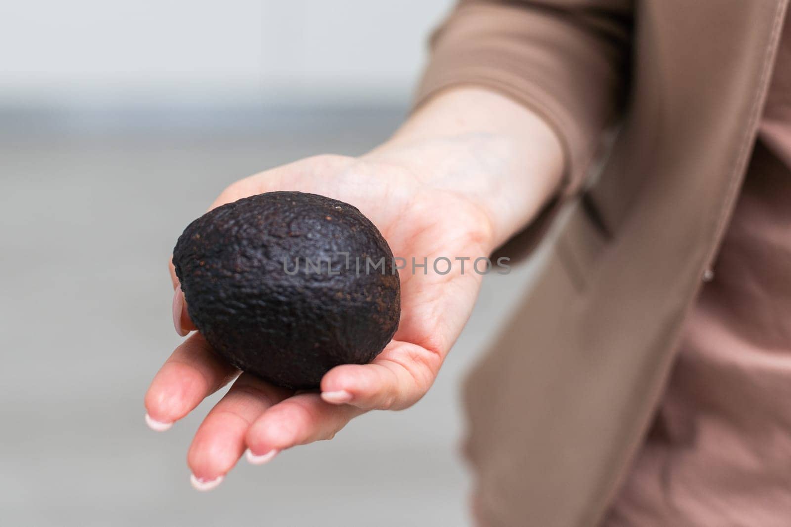 Woman hand holding avocado on white background, closeup. High quality photo