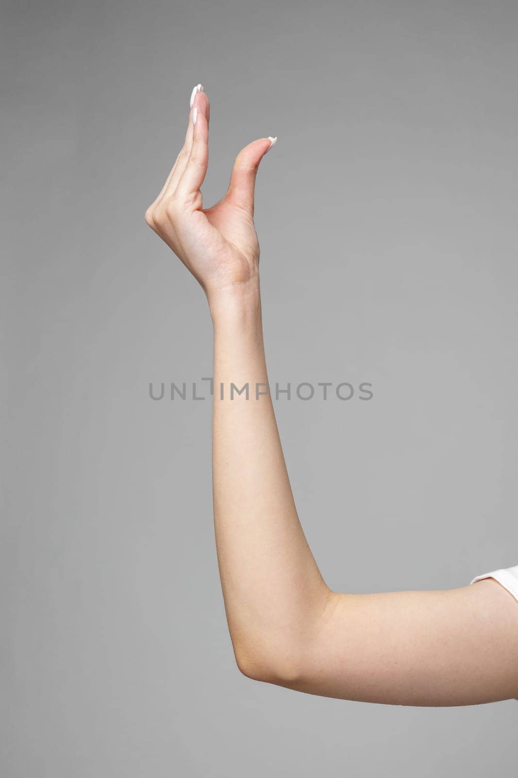 Female hand gesturing sign against gray background close up