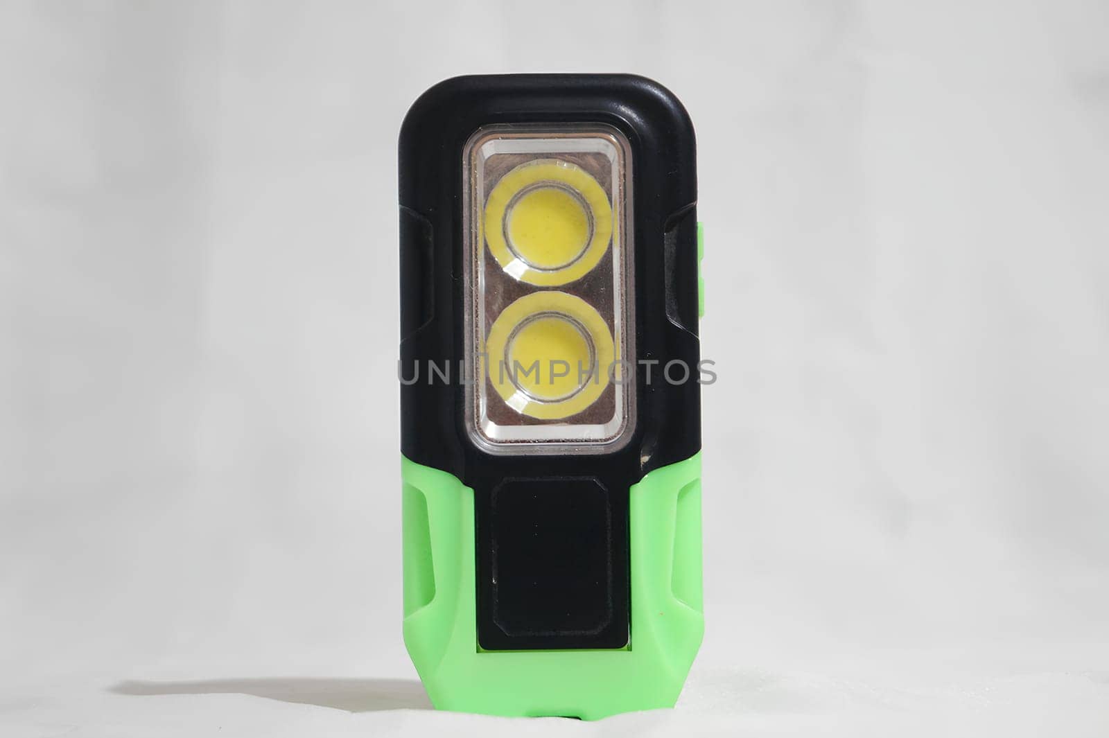 A green and black flashlight with two yellow lights. High quality photo