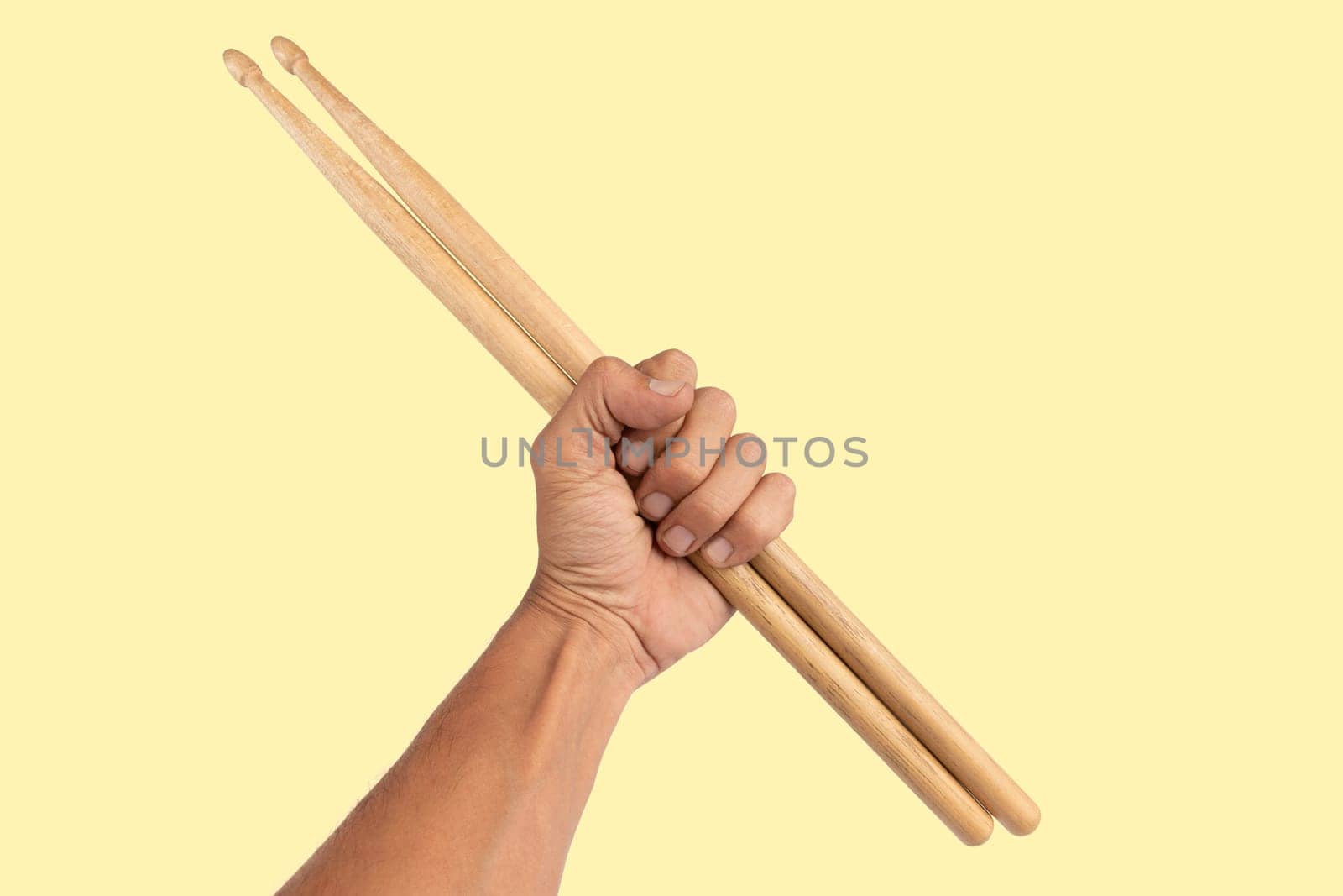 Black male hand holding wooden Drum sticks isolated yellow background. High quality photo