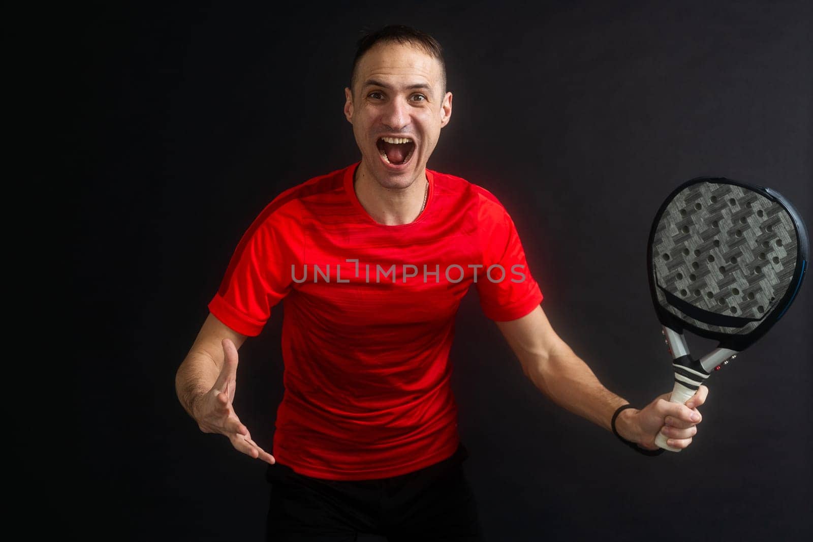 Smiling man with racket and paddle ball dressed in sport clothes isolated background. Front view. High quality photo