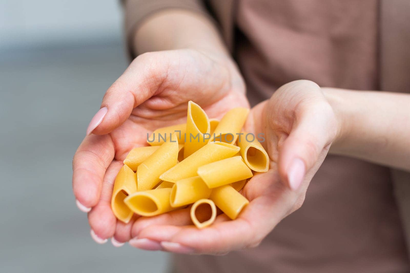 Mostaccioli pasta in the palm of a hand isolated over a white background. High quality photo